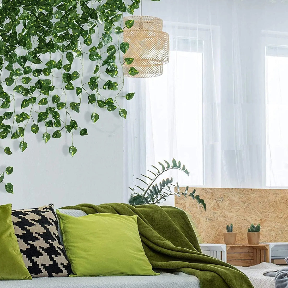 A green artificial ivy leaf garland hangs near a window in a bright room decorated with natural textures and soft fabrics.