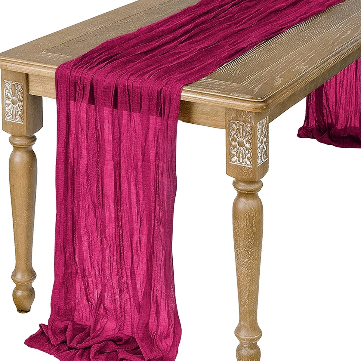 A deep magenta semi-sheer gauze table runner draped over a wooden table.
