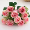 A bouquet of artificial pink and peach roses with green leaves.