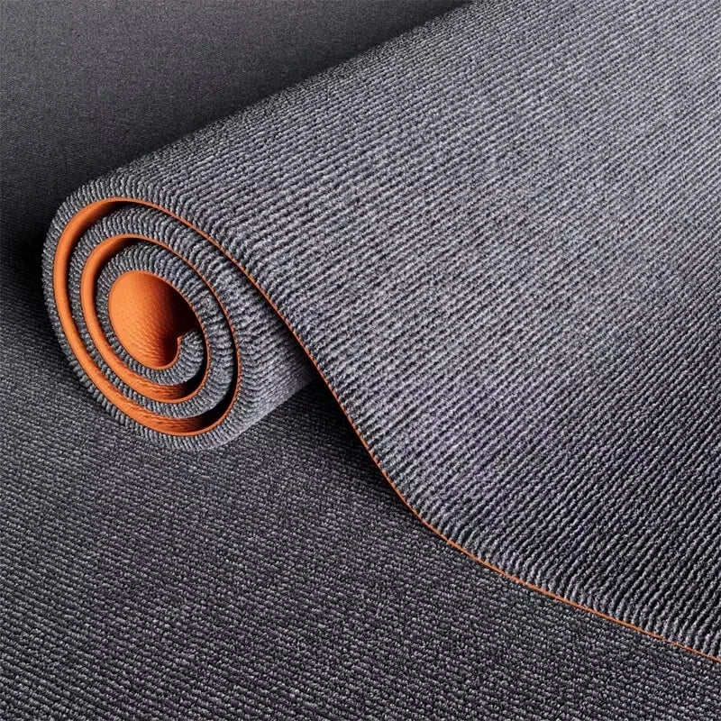 Roll of dark gray artificial grass carpet with an orange accent, showing the texture and weave.