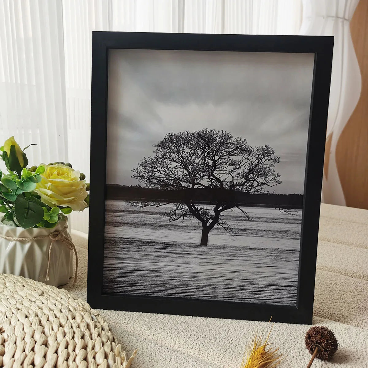 A framed black photograph of a silhouetted tree against a misty landscape.