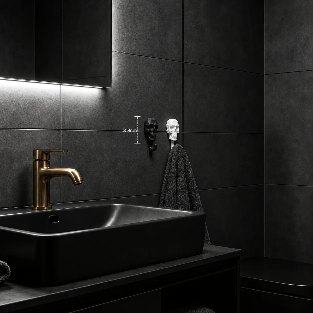 A black vessel sink with a brass faucet is mounted below a dark wall featuring two decorative skull hooks.