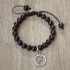 A black beaded bracelet featuring a silver zodiac charm on a dark cord.