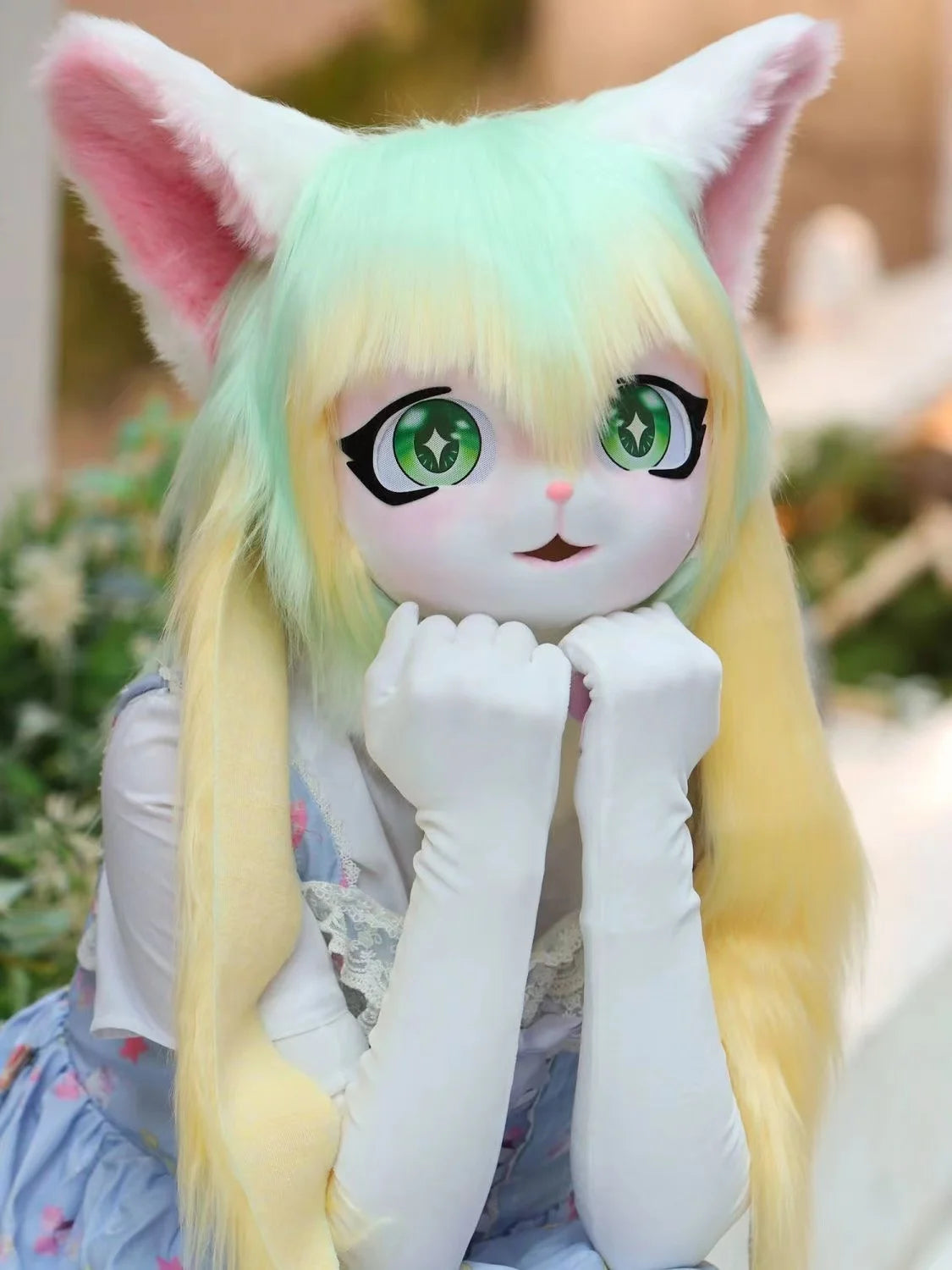 A cute, light green and yellow furry cosplay head with large eyes and long hair.