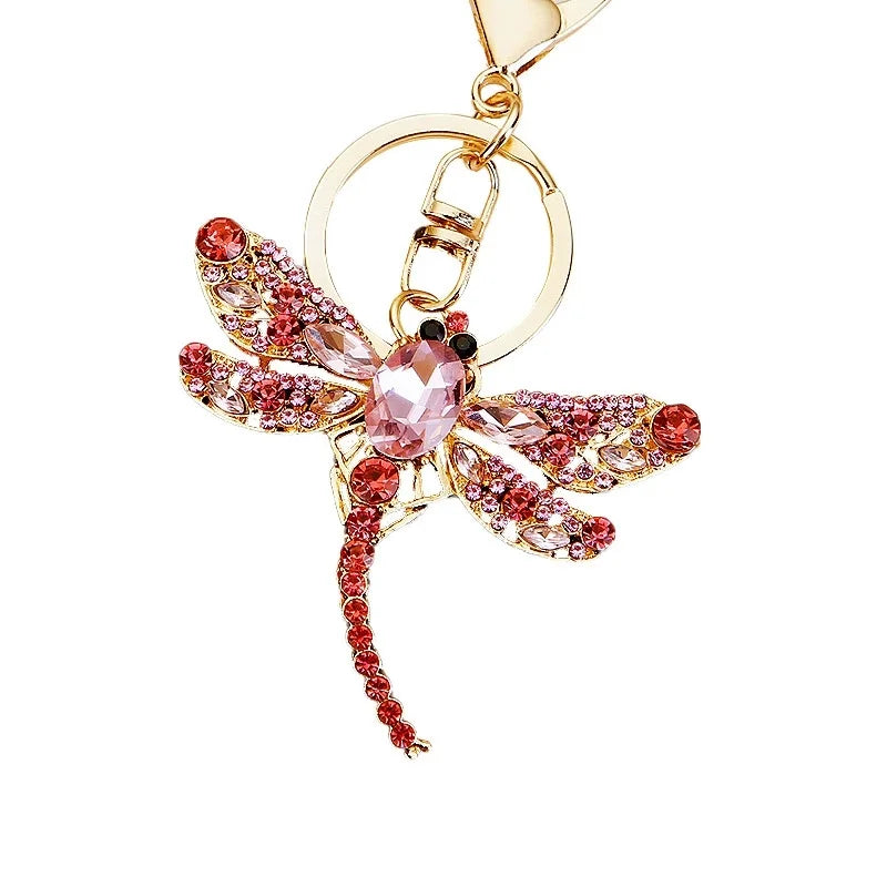 A crystal dragonfly keychain featuring pink and gold accents with a secure carabiner clip.
