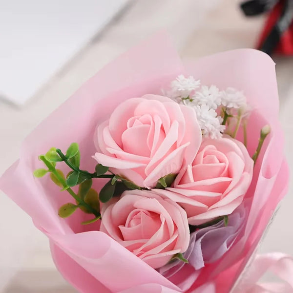 A bouquet of pink artificial mini roses in a sheer pink wrapping.