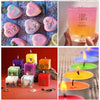 A collection of pink and purple liquid candle dye pigments arranged on a wooden surface.