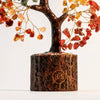 A small, dark wood tree ornament with branches adorned by various colored crystal beads.
