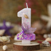 A birthday candle shaped like the number one decorated with purple glitter and a starfish design.