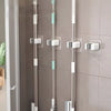 Three silver and white self-adhesive wall holders for storing mops, brooms, and long-handled tools.