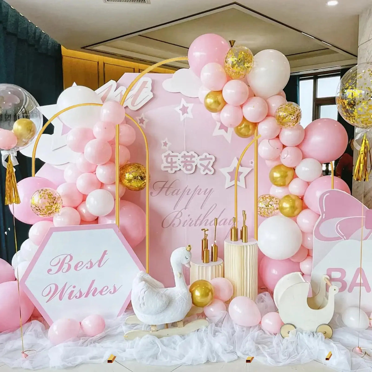 A pink and gold balloon backdrop featuring white and pink balloons and a unicorn design for a birthday celebration.