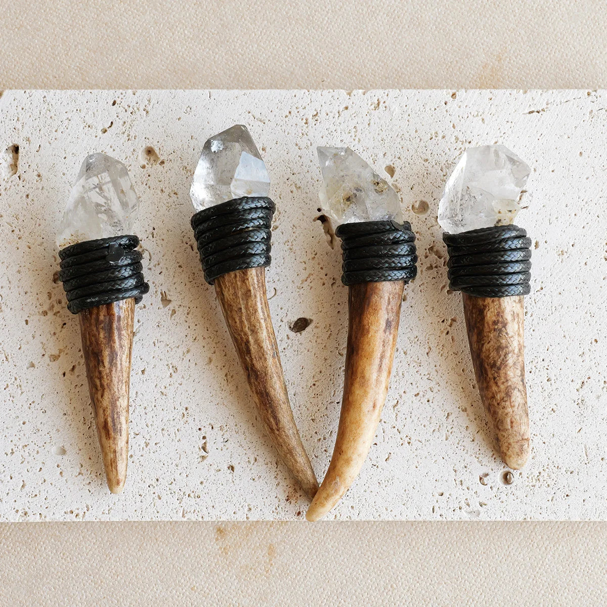 Four natural crystalHerkimer scepter wands with clear stones and black wrappings displayed on a light surface.