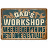 A distressed metal sign with the text Dad's Workshop Where Everything Gets Done Eventually on a teal background.