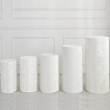 Five cylindrical white spandex covers displayed against a white paneled wall.