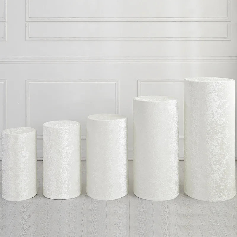 Five cylindrical white spandex covers displayed against a white paneled wall.