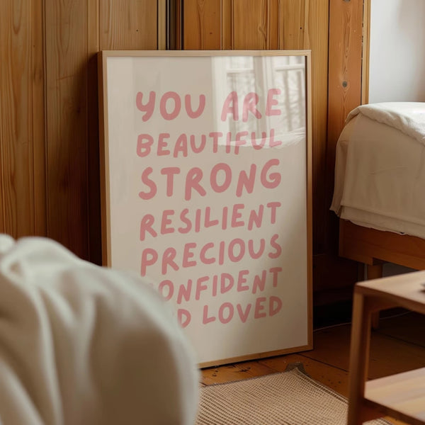 A framed canvas print with pink text that reads You are beautiful strong resilient precious confident and loved hanging on a 