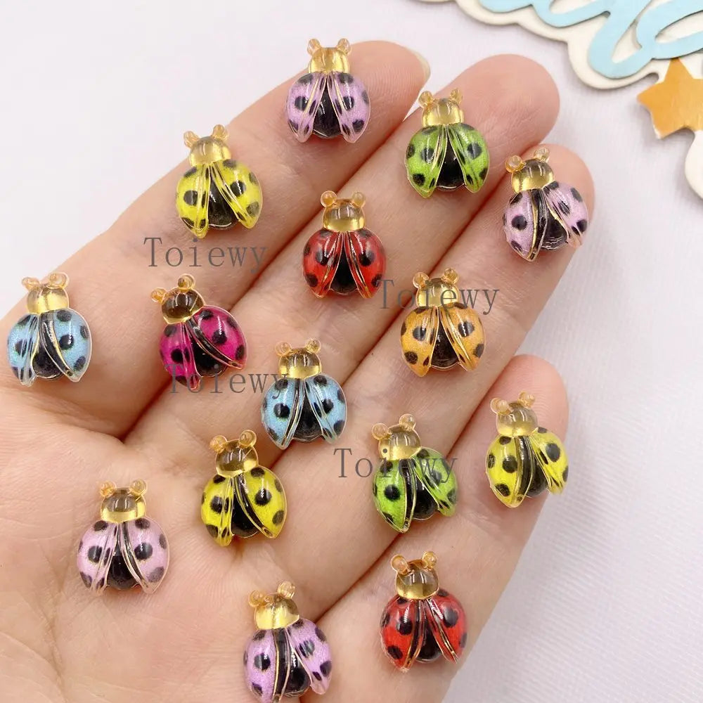 A collection of colorful resin beetle rhinestone appliques for DIY crafts displayed on a hand.