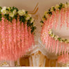 A large floral chandelier featuring pink and white silk wisteria hanging vine garlands in a grand interior setting.