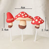 A set of three red and white polka-dotted mushroom cake toppers on wooden sticks.