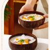 Three dark brown coconut shell serving bowls filled with a creamy, orange-colored food mixture.
