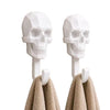 A pair of white 3D skull wall hooks designed for hanging towels, coats, and other items.