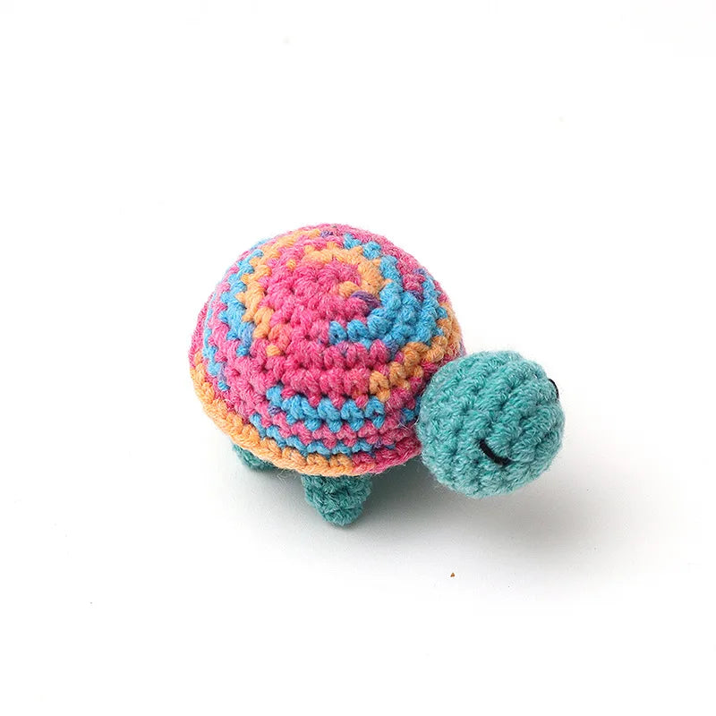 Handmade crocheted turtle plush with a vibrant pink and orange shell and green body.