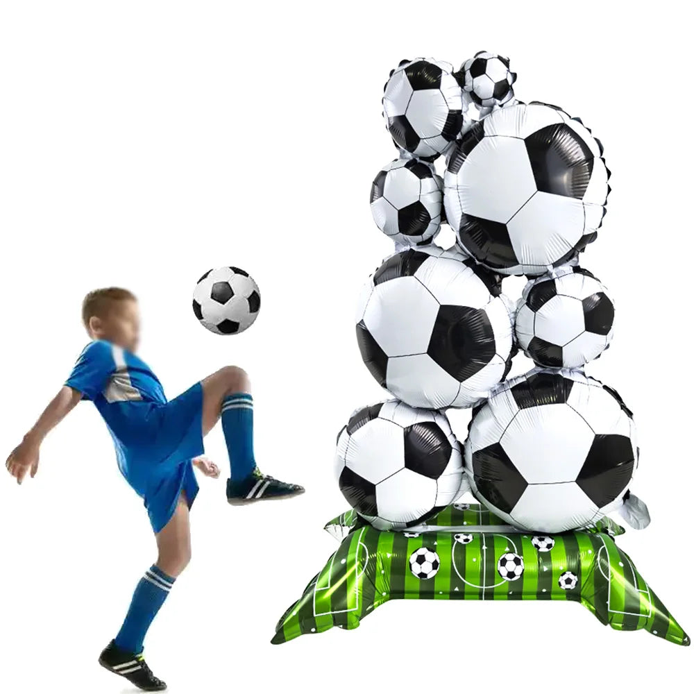 A stack of white soccer balls used as party décor, with a child in a blue shirt nearby.