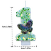 A tall candle shaped like the number one decorated with green sequins and a purple butterfly