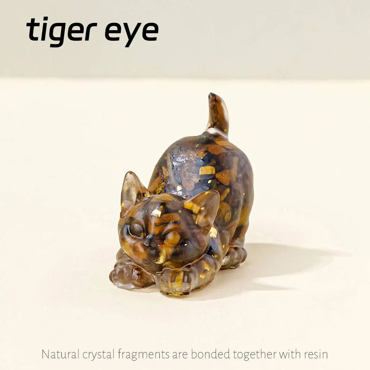 A small, amber-colored crystal figurine of a crouching cat made from natural crystal fragments and resin.