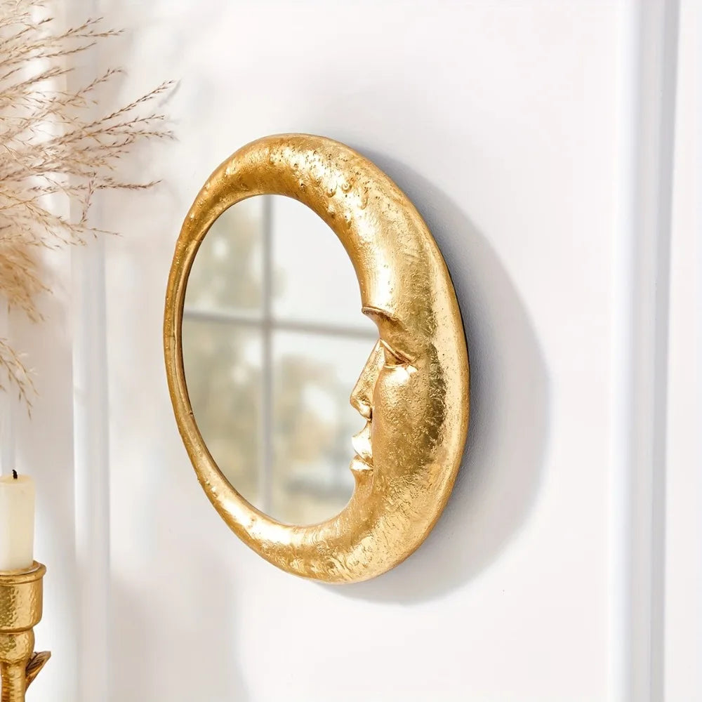 A round, gold resin decorative hanging mirror with an organic, crescent shape mounted on a white wall.