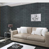 A beige sofa is placed in front of a dark gray brick wall panel featuring a minimalist floral artwork.