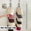 A hand is hanging a beige hat onto a silver clip organizer rack for closet storage.