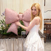 A young woman holds a large pink pearl bow balloon weight for party celebrations.