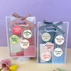 Klares Plastikverpackung mit Dankesnote und runden Blumenstickern, gebunden mit rosa und blauer Schleife