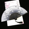 A vintage silk folding fan with gray and white oriental floral patterns is displayed against a light background.
