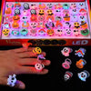 A hand holds various Halloween LED glow rings featuring pumpkin, ghost, and spider designs.