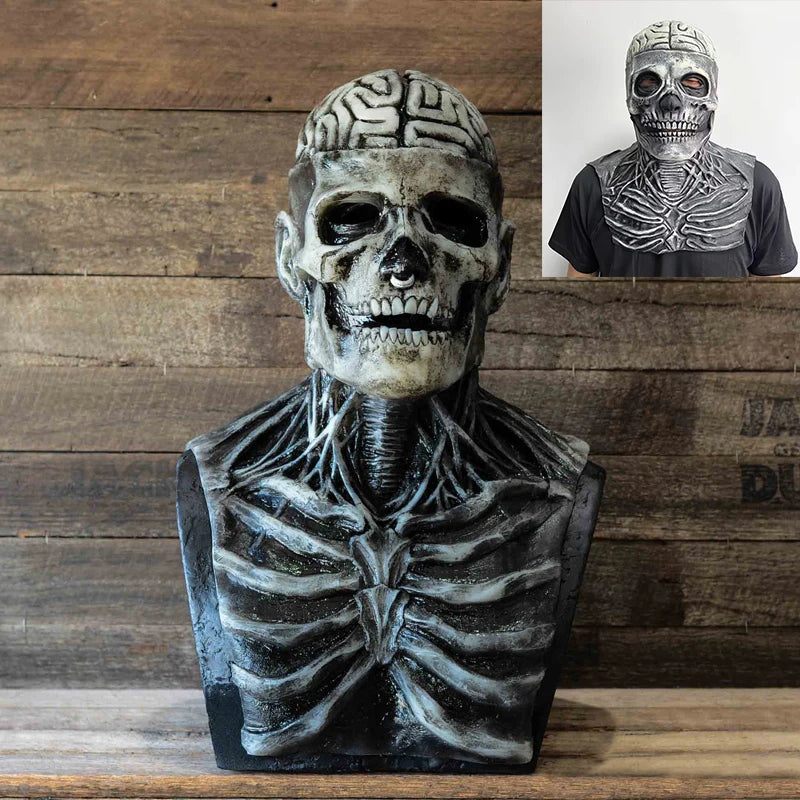 A realistic latex skull mask with intricate bone detailing and a patterned skull helmet displayed on a wooden surface.