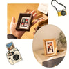 A hand holds a wooden photo frame displaying small polaroid pictures, next to a vintage camera.