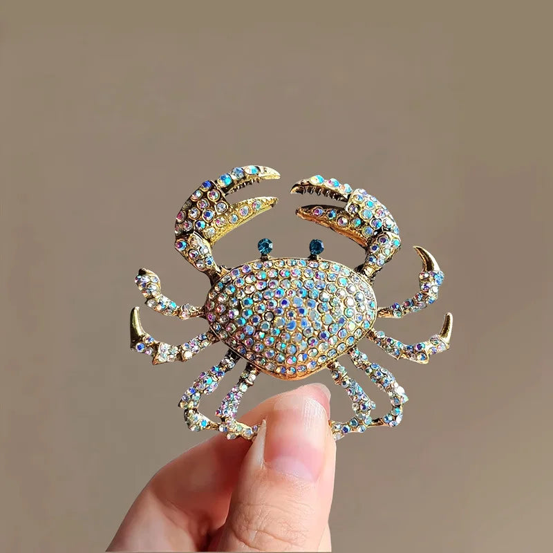 A close-up of a vintage marine life brooch pin set featuring a detailed gold and iridescent crab design.