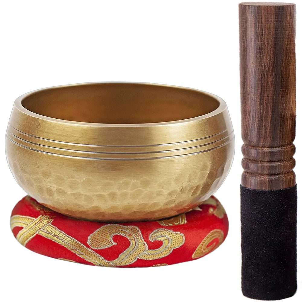 A handcrafted copper singing bowl set featuring a golden bowl and a dark wooden mallet.