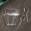 A collection of clear plastic disposable spoons arranged on a dark surface.