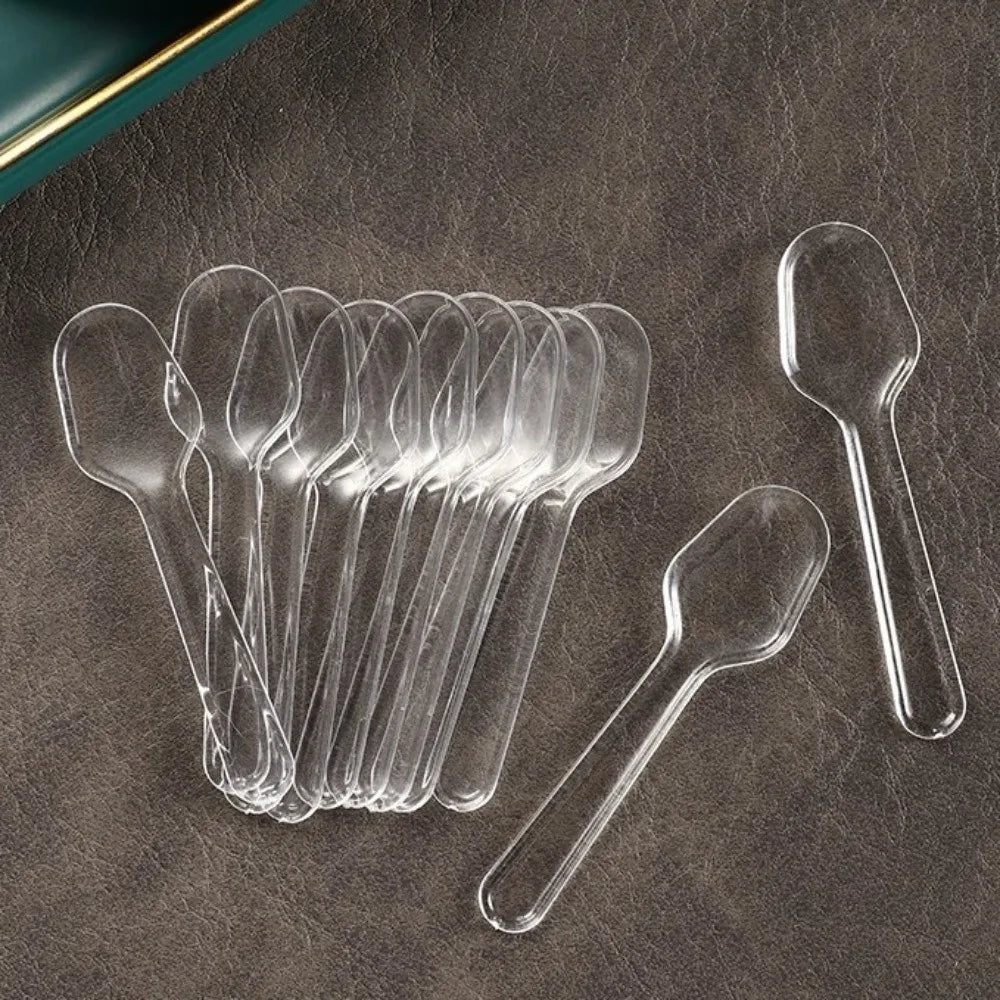 A collection of clear plastic disposable spoons arranged on a dark surface.