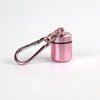 A small, pink, cylindrical pill organizer is attached to a silver keychain ring.