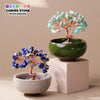 Handcrafted crystal tree with a copper wire base growing out of a green bowl and a light stone dish.