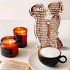 A wooden acrylic sign shaped like a lion, engraved with a message to Dad, placed next to a mug of coffee.