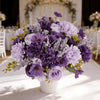 A vibrant bouquet of artificial mixed flowers featuring purple, lavender, and mauve roses, daisies, and chrysanthemums.