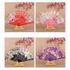 Three folding silk flower fans in pink, white, and purple shades displayed on a wooden stand.