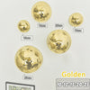 A collection of gold disco balls of various sizes mounted on a white wall.
