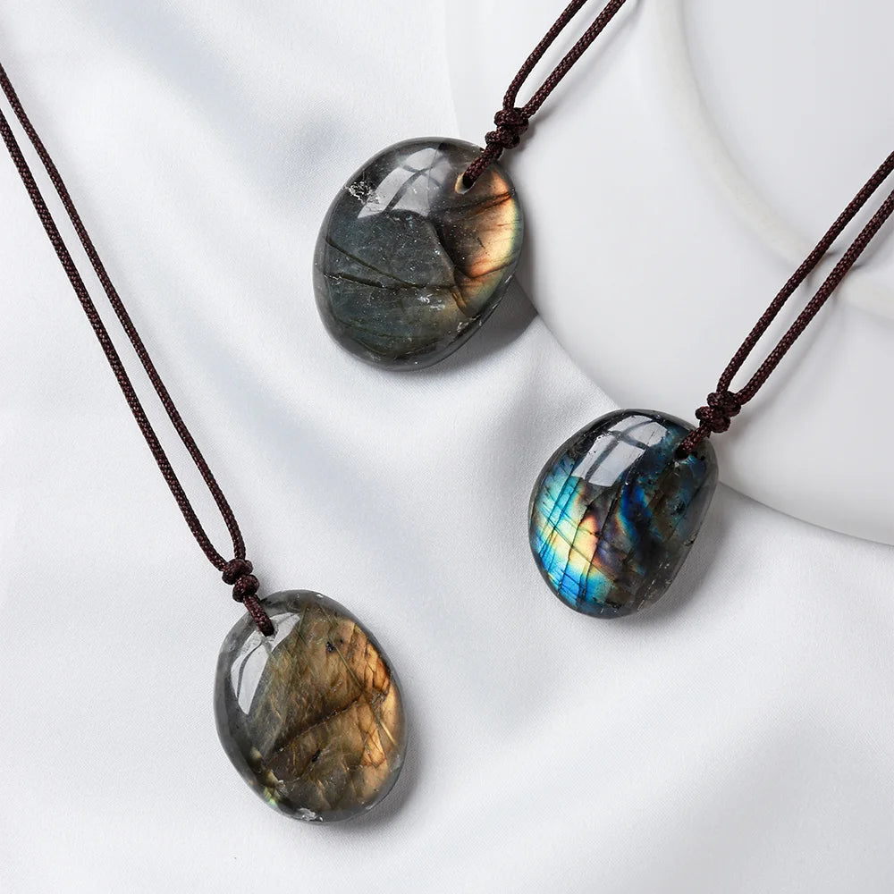 A necklace featuring three polished, oval labradorite stones with iridescent blue and gold flashes on a dark background.