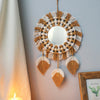 Boho macrame round wall mirror with fringe and leaf accents hanging on a gray wall.